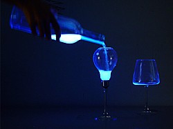 Flüssiges Licht wird aus einer Flasche in ein Glühbirnen-Glas geschüttet