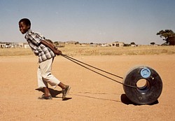 Junge zieht Wassertransport Rollreifen Q Drum